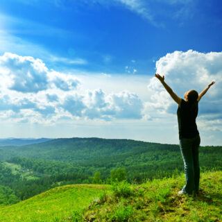 Longevity – Der Frühling als Katalysator für zelluläre Erneuerung Frau auf einem grünen Berg als Symbol für Longevity und Gesundheit
