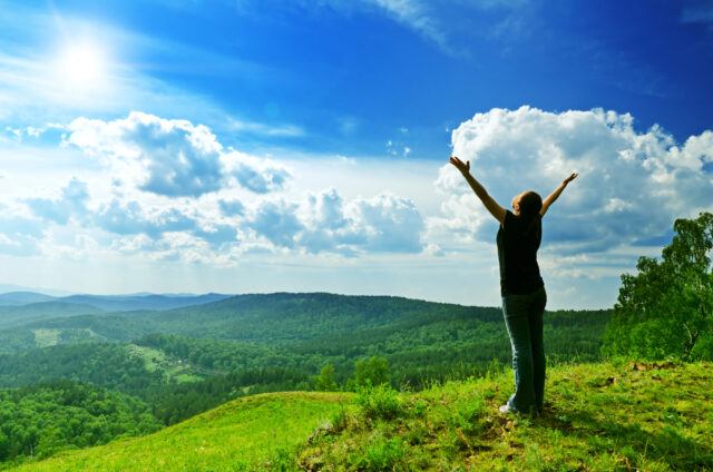 Frau auf einem grünen Berg als Symbol für Longevity und Gesundheit